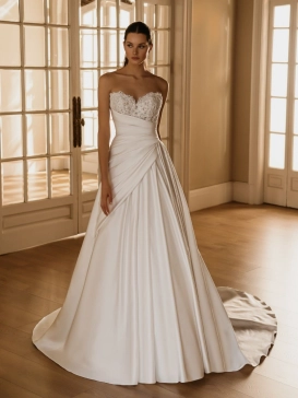 HERMIONE by ÉLYSÉE is a romantic A-line wedding dress featuring a sparkling embellished sweetheart bodice, softly draped satin skirt, and elegant cathedral train.